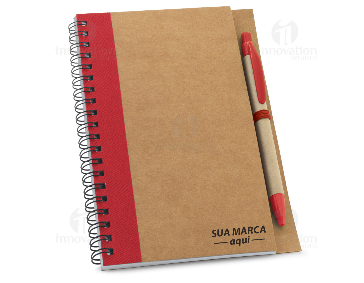 Caderno B6 espiral de capa dura em cartão, com 120 páginas lisas em papel reciclado e suporte para esferográfica (inclusa). 