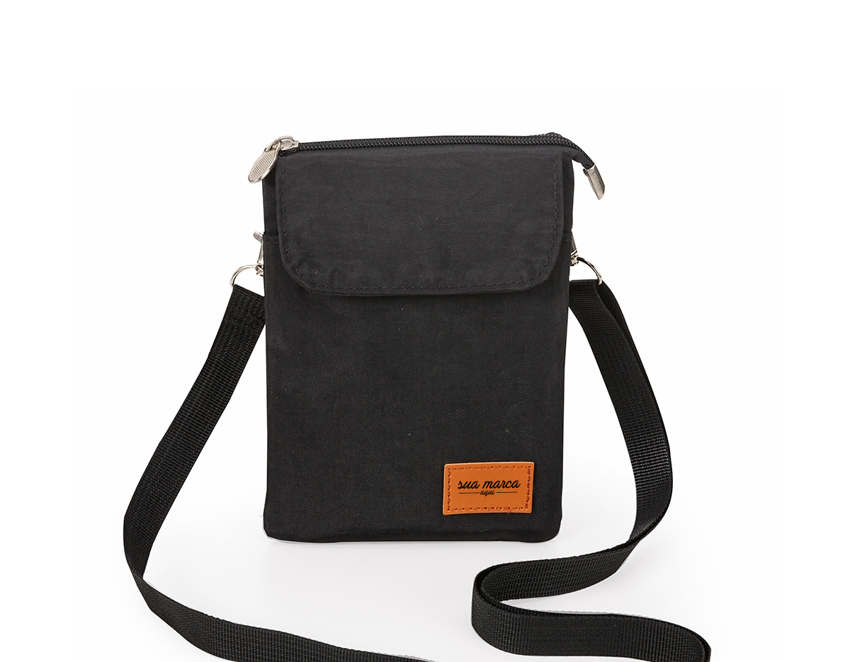 Mini bolsa transversal de nylon com plaquinha frontal em couro sintético personalizável. Possui tecido impermeável, bolso frontal com botão de fechamento imantado, bolso traseiro de zíper e bolso superior de zíper com duas divisórias internas e espaço para celular. Acompanha alça ajustável de uso transversal (removível).