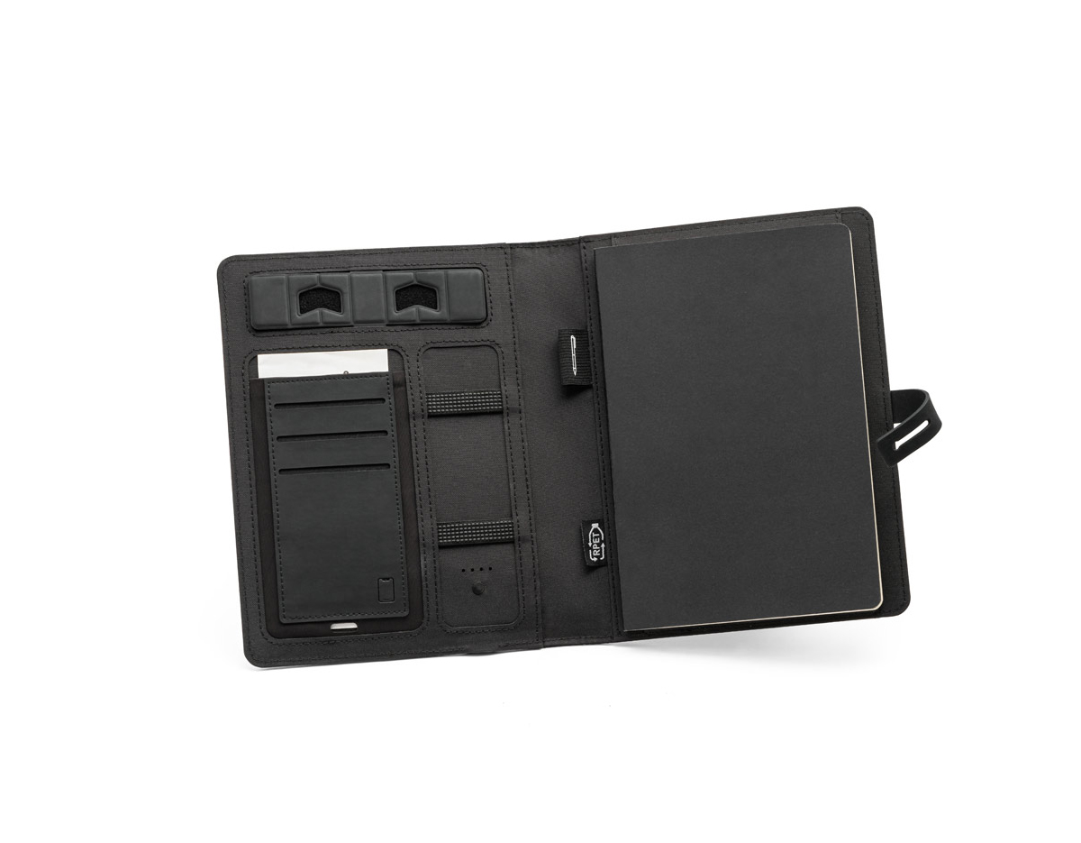 Pasta A5 em 300D poliéster reciclado (100% rPET) com carregador wireless embutido. A bateria tem capacidade para 5.000 mAh, potência de 10W, entrada/saída 5V/2.1A e cabo USB tipo C para carregar a bateria. A pasta contém no seu interior um bolso para smartphone até 6.5'', três espaços para cartões, quatro luzes LED, botão on/off, suportes para esferográfica (não inclusa), celular e cabo USB, um bloco de notas com capa em cartão preto e 64 folhas pautadas de cor marfim, em papel proveniente de gestão florestal sustentável. Na frente existe ainda uma impressão oval em preto para indicar a área de carga do wireless. Fornecido em caixa presente. 165 x 225 x 25 mm