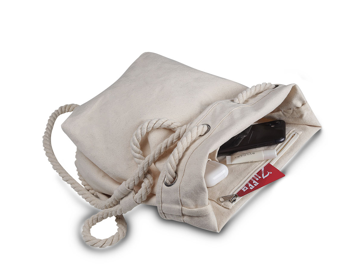 Sacola/mochila produzida em algodão cru, versátil e prática. Conta com alça lateral e alças trançadas para uso como mochila. Possui compartimento interno, ideal para organizar objetos de forma eficiente.