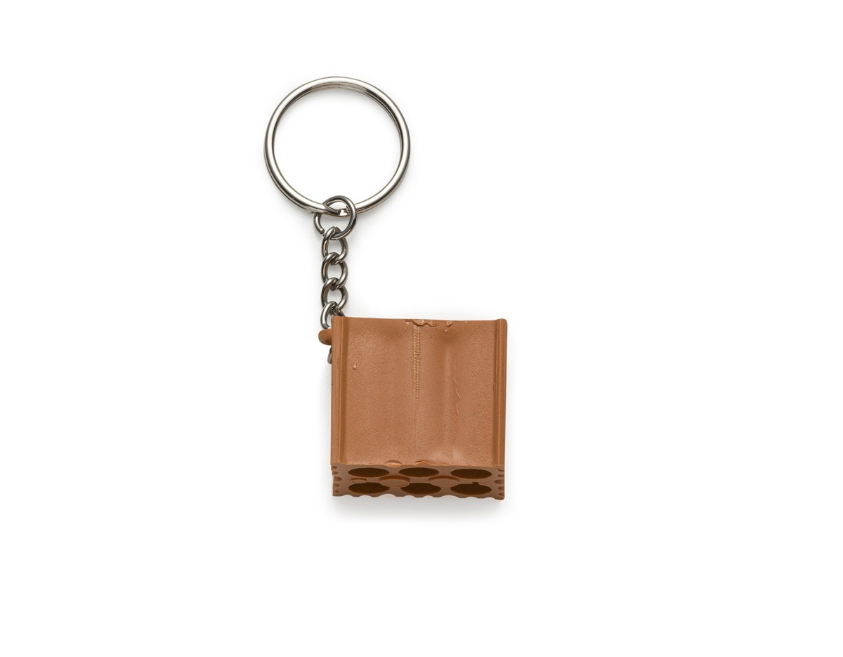 Chaveiro de plástico em formato de tijolo, com um lado liso ideal para personalização. O outro lado é totalmente em relevo, destacando o formato. Ideal para quem busca um item funcional e com possibilidade de personalização para diferentes finalidades.