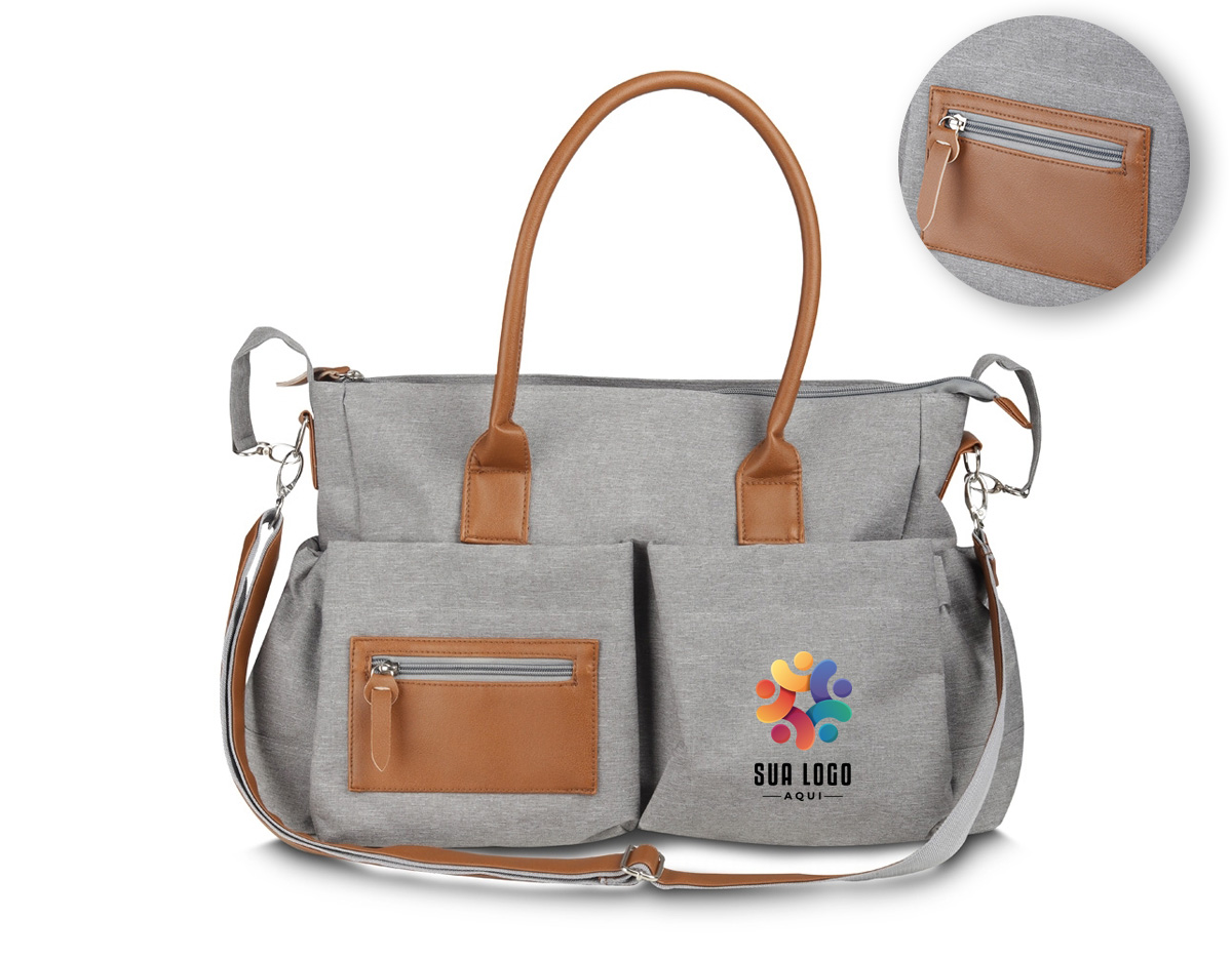 Nossa bolsa multifuncional de 17 litros foi pensada para atender diferentes necessidades do dia a dia. Feita em poliéster com tecido resistente à água, ela traz detalhes em couro sintético que dão um toque moderno e sofisticado. Por dentro, é totalmente forrada em nylon e tem um espaço amplo com quatro bolsos, facilitando a organização de tudo o que for necessário. O fechamento principal é por zíper, com um charmoso detalhe em couro sintético. Já na parte externa, são seis bolsos ao todo: um com fechamento em zíper e detalhe em couro sintético, dois nas laterais e outros três com botão de ímã, garantindo praticidade e segurança para pequenos objetos. Para maior conforto, as alças permitem o uso tanto no ombro quanto nas mãos. E para quem precisa de ainda mais versatilidade, a bolsa conta com uma alça extra produzida em poliéster e detalhe em couro sintético ajustável e removível, além de um suporte, perfeito para prender em carrinhos de bebê, supermercado ou onde desejar. Essa bolsa é uma excelente opção de brinde, unindo modernidade e praticidade.