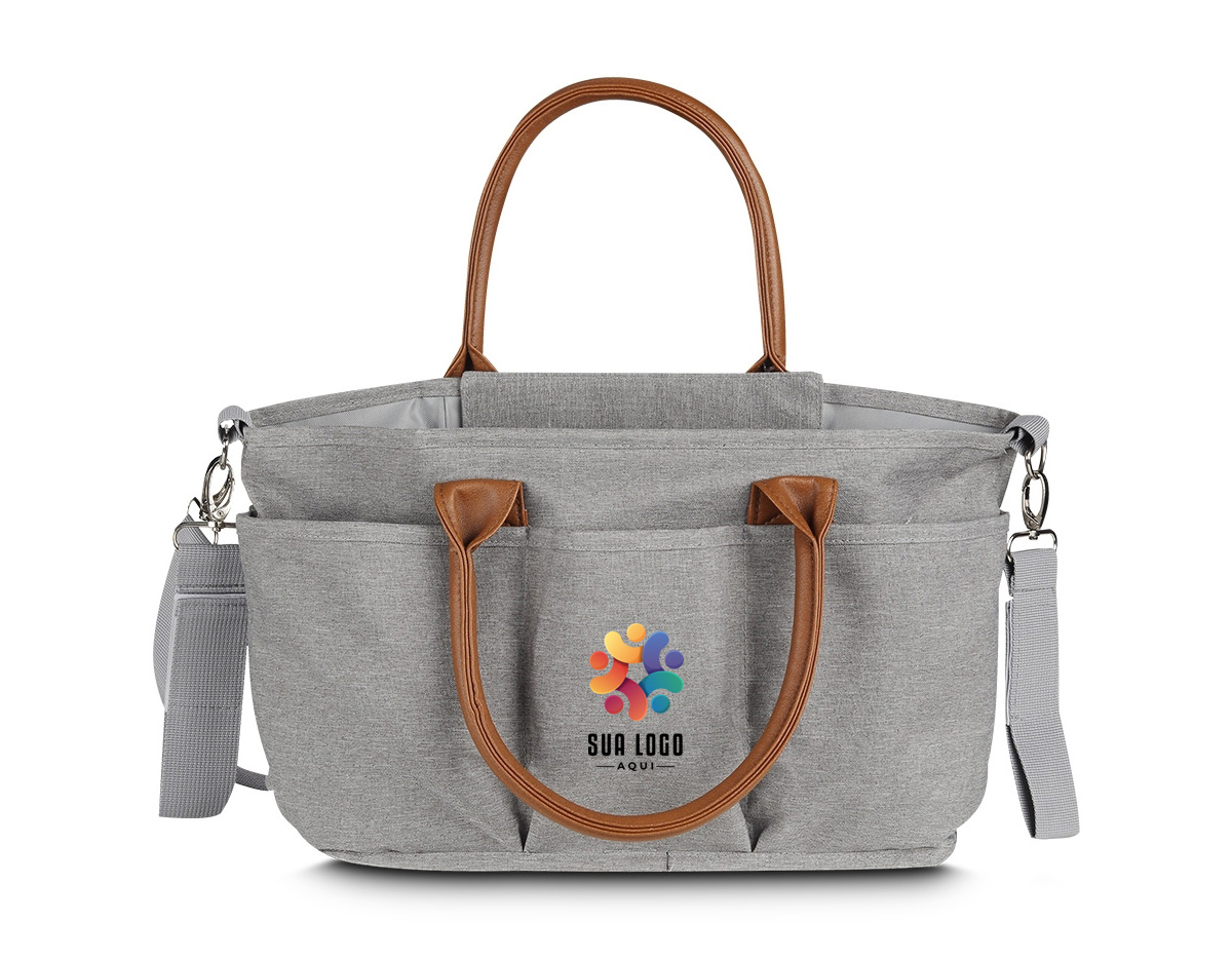 Nossa bolsa multifuncional de 8 litros é projetada para se adaptar a diferentes ocasiões. Produzida em poliéster com tecido resistente à água, possui alças em couro sintético que combinam com um design moderno e prático, ideal para guardar diversos itens, como os de bebê, trabalho e afins. A parte interna oferece um espaço amplo e adaptável, com duas divisórias contendo velcro que permitem criar até três compartimentos separados. Além disso, possui um bolso com zíper e três bolsos internos, sendo um deles com elástico para facilitar o acesso. O fechamento da bolsa é feito por um compartimento que protege a parte central. Para torná-la ainda mais funcional, conta com um compartimento térmico integrado, ajudando a manter a bebida na temperatura ideal por mais tempo. Na parte externa, há cinco bolsos adicionais, além de um engate de nylon com fechamento em velcro, perfeito para prender em carrinhos de bebê ou onde desejar. Suas alças podem ser usadas no ombro ou nas mãos. Além disso, conta com uma alça extra ajustável e removível, oferecendo mais versatilidade sempre que necessário. Essa bolsa é uma excelente opção de brinde, unindo modernidade e praticidade.