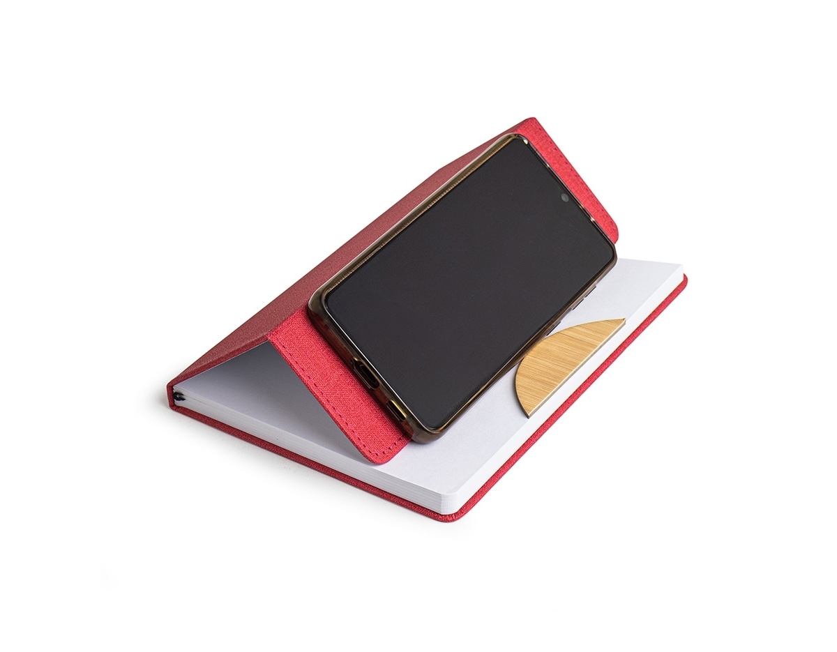 A nossa caderneta traz funcionalidade e estilo em um design leve e prático. Feita em rPET, com cerca de 96 folhas brancas pautadas, é perfeita para anotações, e conta com um suporte na capa feito de papelão, com revestimento similar ao bambu, ideal para manter o aparelho celular firme. A capa dobrável e flexível facilita o transporte, e o marcador de página em cetim agrega um toque de sofisticação.