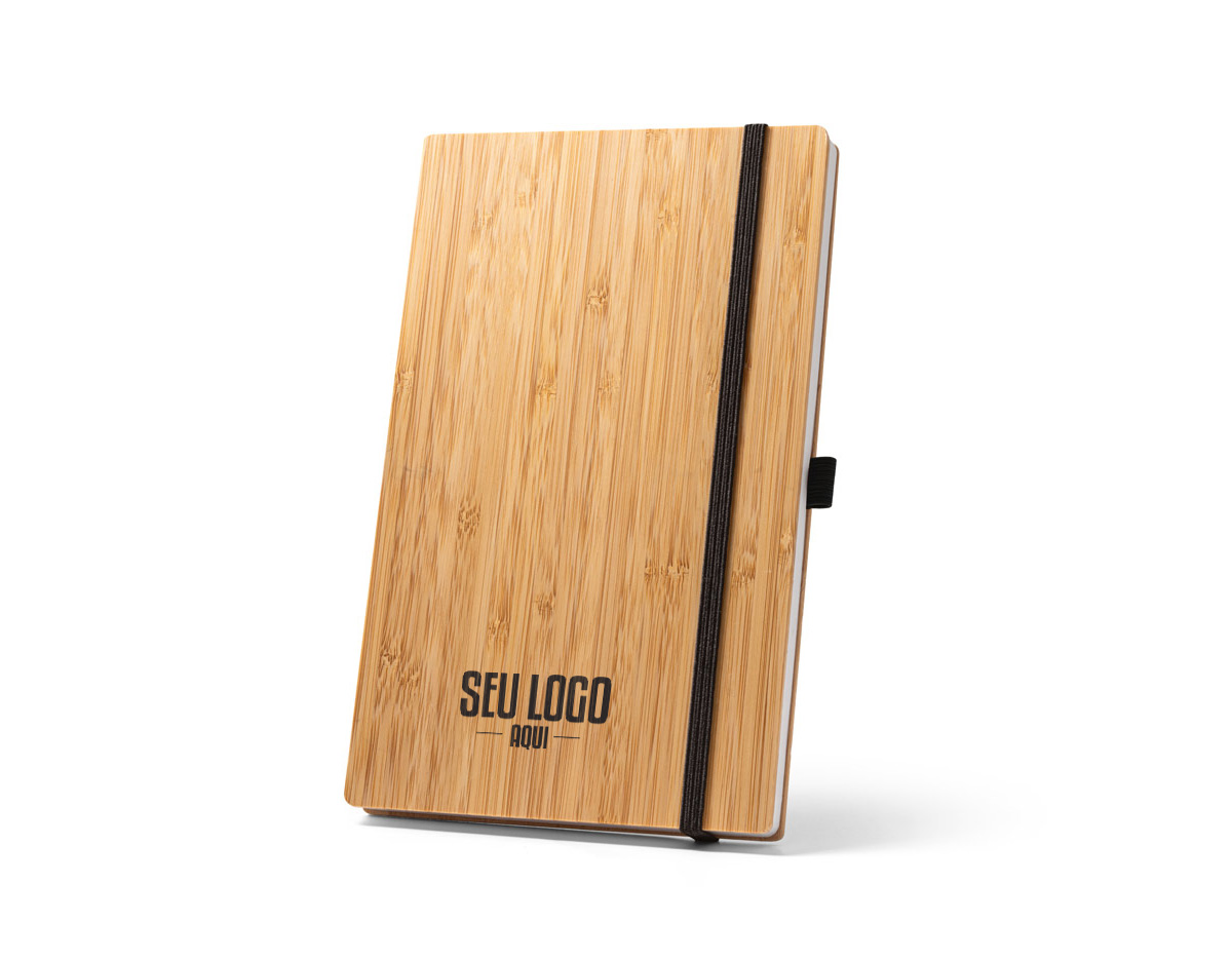 Caderno de bolso de capa e contracapa em placa de bambu e lombada em poliéster 100% reciclado (100% rPET). O interior contém 80 folhas lisas com papel reciclado, suporte para esferográfica (não inclusa) e elástico para fecho do caderno. A cor e o resultado da impressão nos materiais naturais pode variar entre produtos. 90 x 140 mm