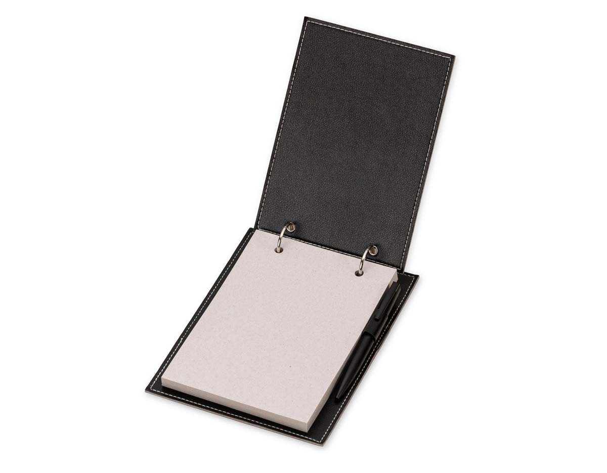 Bloco de anotações de mesa com trilho de ferro e capa em couro sintético. Contém suporte interno lateral para caneta (não inclusa) e cerca de 96 folhas recicladas com área destacável para facilitar o uso no dia a dia.