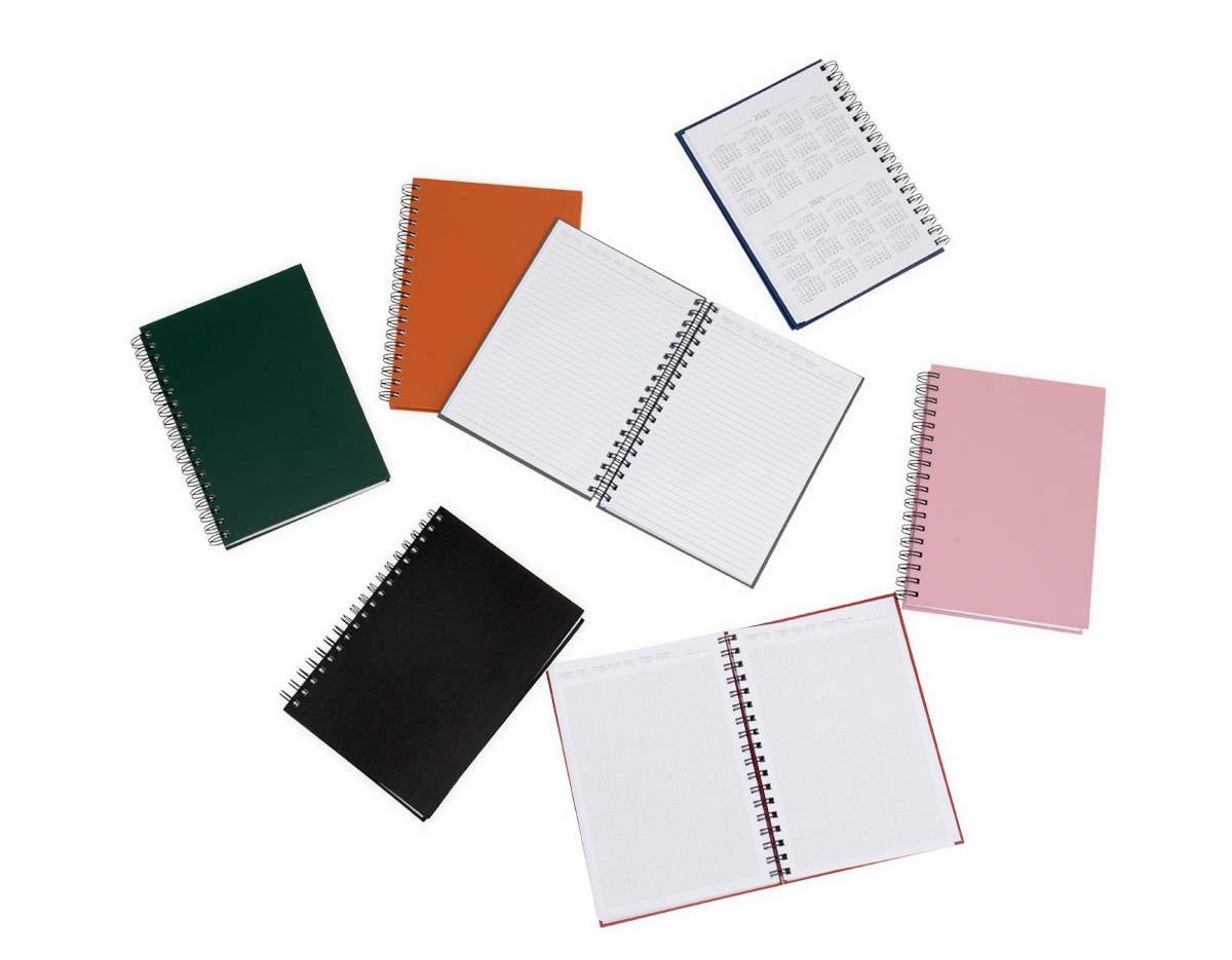 Caderno com capa em cromato e wire-o metálico. Possui aproximadamente 86 folhas pautadas e páginas para: dados pessoais, calendários de 2023 à 2025, planejamentos e endereços de contatos.