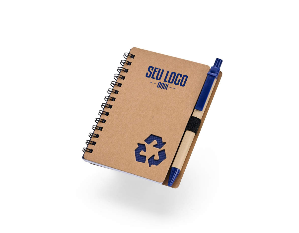 Caderno com capa de papelão e detalhe vazado em forma de símbolo de reciclagem. Possui encadernação Wire-O, cerca de 70 folhas pautadas brancas e elástico para caneta. Acompanha esferográfica azul (1,0 mm), com corpo em papelão, clique e ponteira plástica. Ideal para anotações diárias.