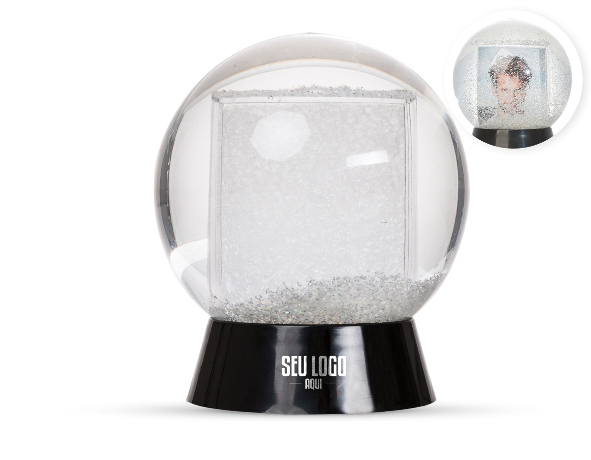Globo de neve em plástico resistente, com glitter interno e porta-foto. A base preta é removível para inserção de uma foto no suporte interno, com dimensões de 8,5 cm x 4,7 cm, unindo decoração e funcionalidade em um só item.