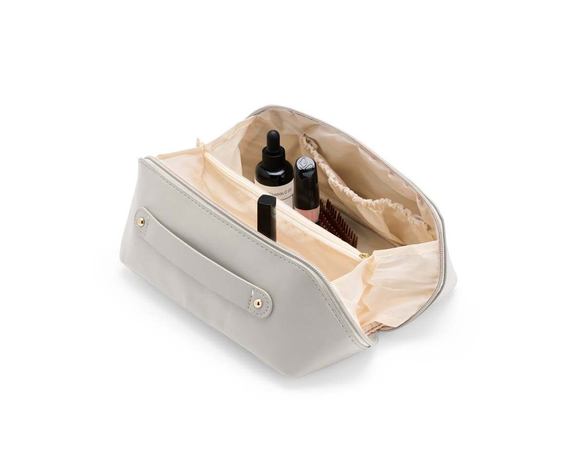 Nécessaire em poliuretano (PU) impermeável com abertura em 180 graus inspirada no formato de concha. O compartimento interno conta com dois bolsos laterais abertos e um, localizado na parte central, com fechamento em zíper. Possui alça para transporte.

