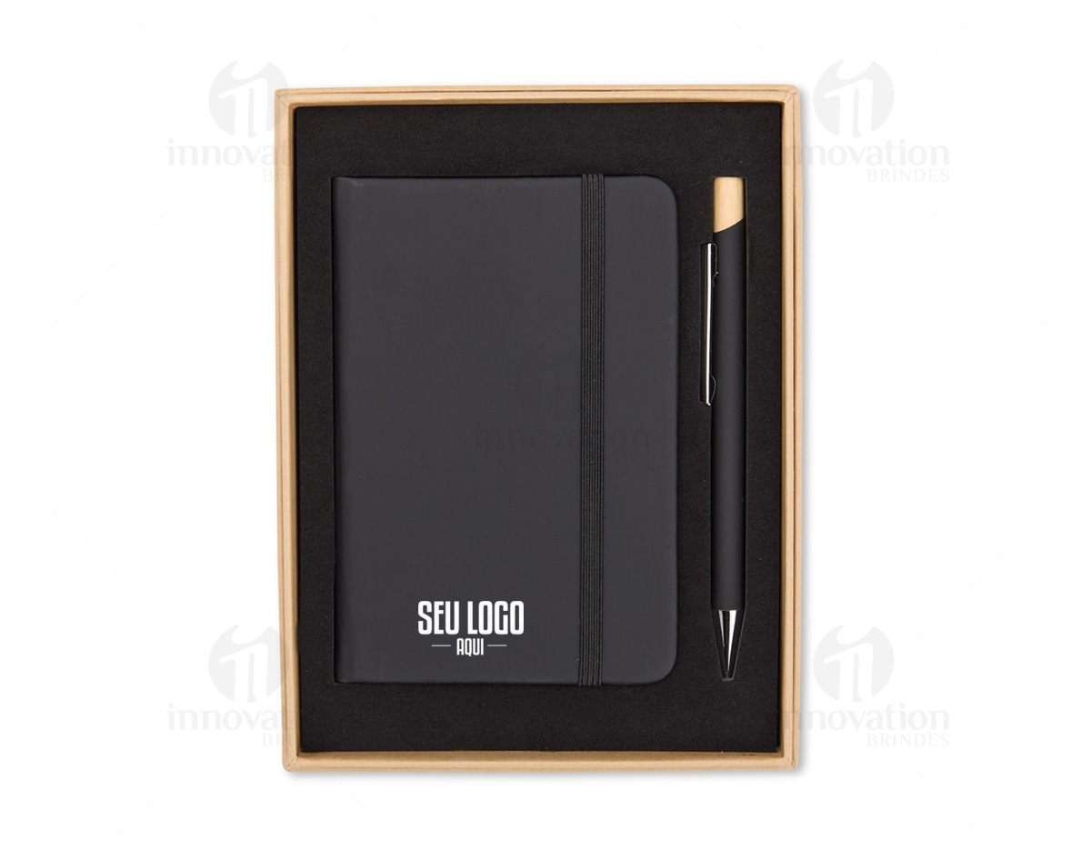 Kit executivo composto por uma caderneta e uma caneta. A caderneta possui capa dura, marca-páginas em fita de cetim e elástico para fechamento, além de aproximadamente 80 folhas com pauta. Por sua vez, a caneta metálica conta com detalhe em bambu, acionamento por clique e carga esferográfica azul de 1,0mm. Acompanha uma caixa de papelão com berço interno em espuma.